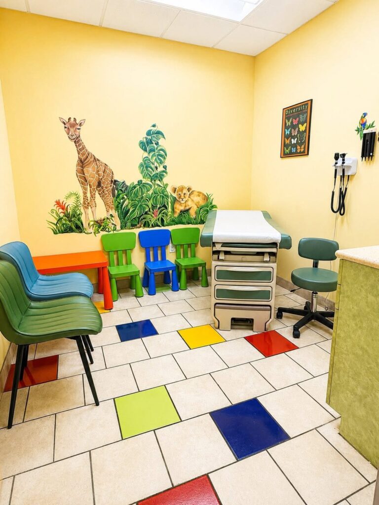 An exam room with a jungle mural and child-size chairs